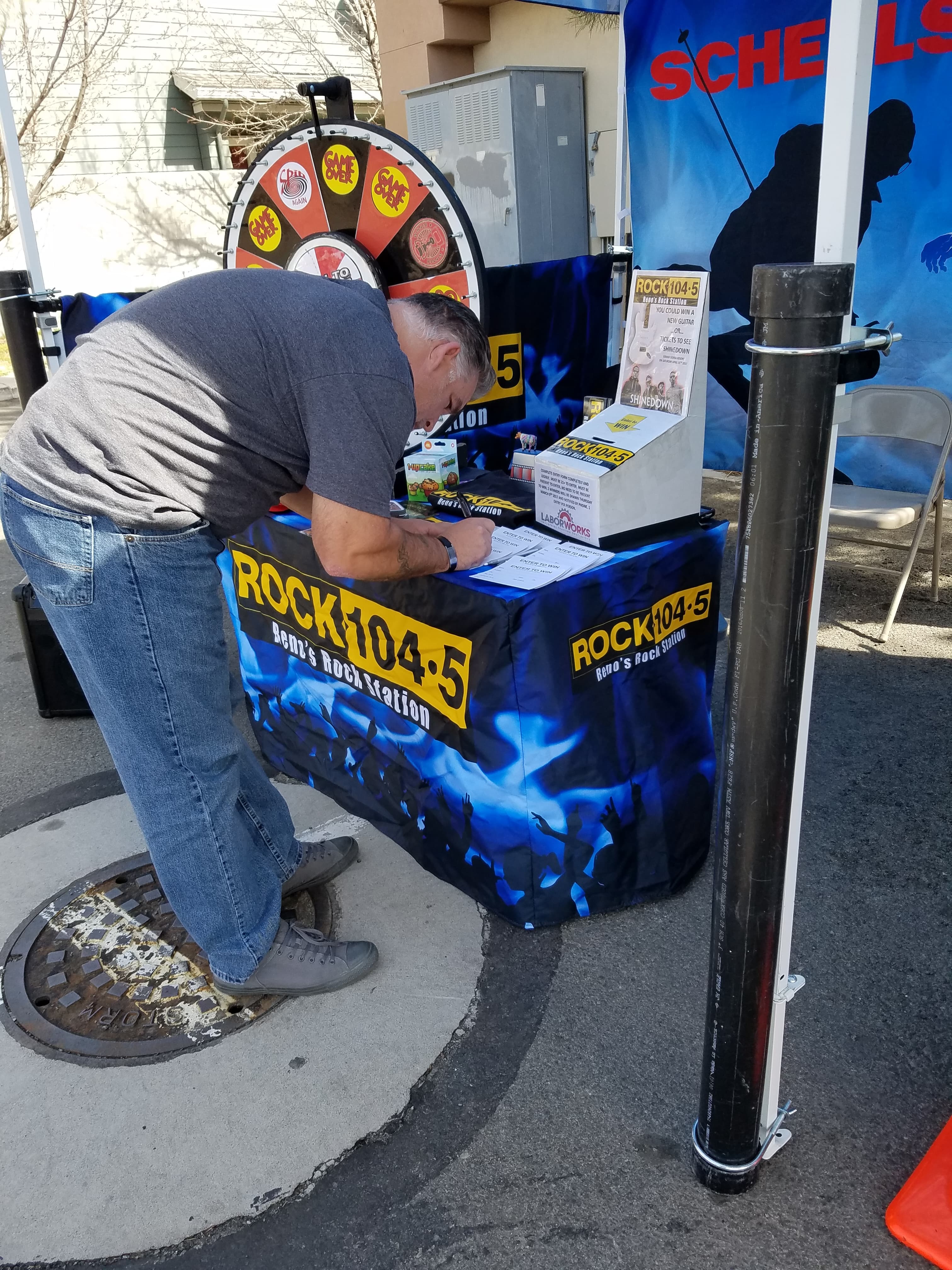Man working the ROCK104.5 promo table with prize wheel at event